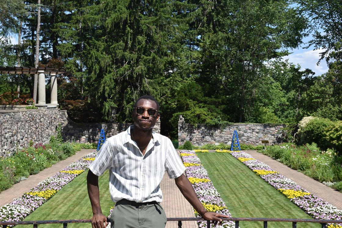 Photograph of a visitor on the porch above the Sunken Garden at Cranbrook House & Gardens, July 2019.