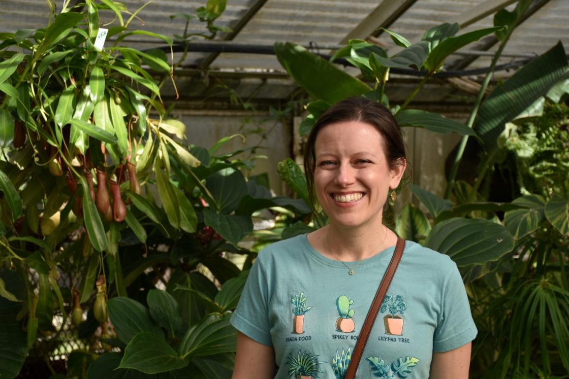 Photograph of a smiling visitor in the Cranbrook House & Gardens Greenhouse.